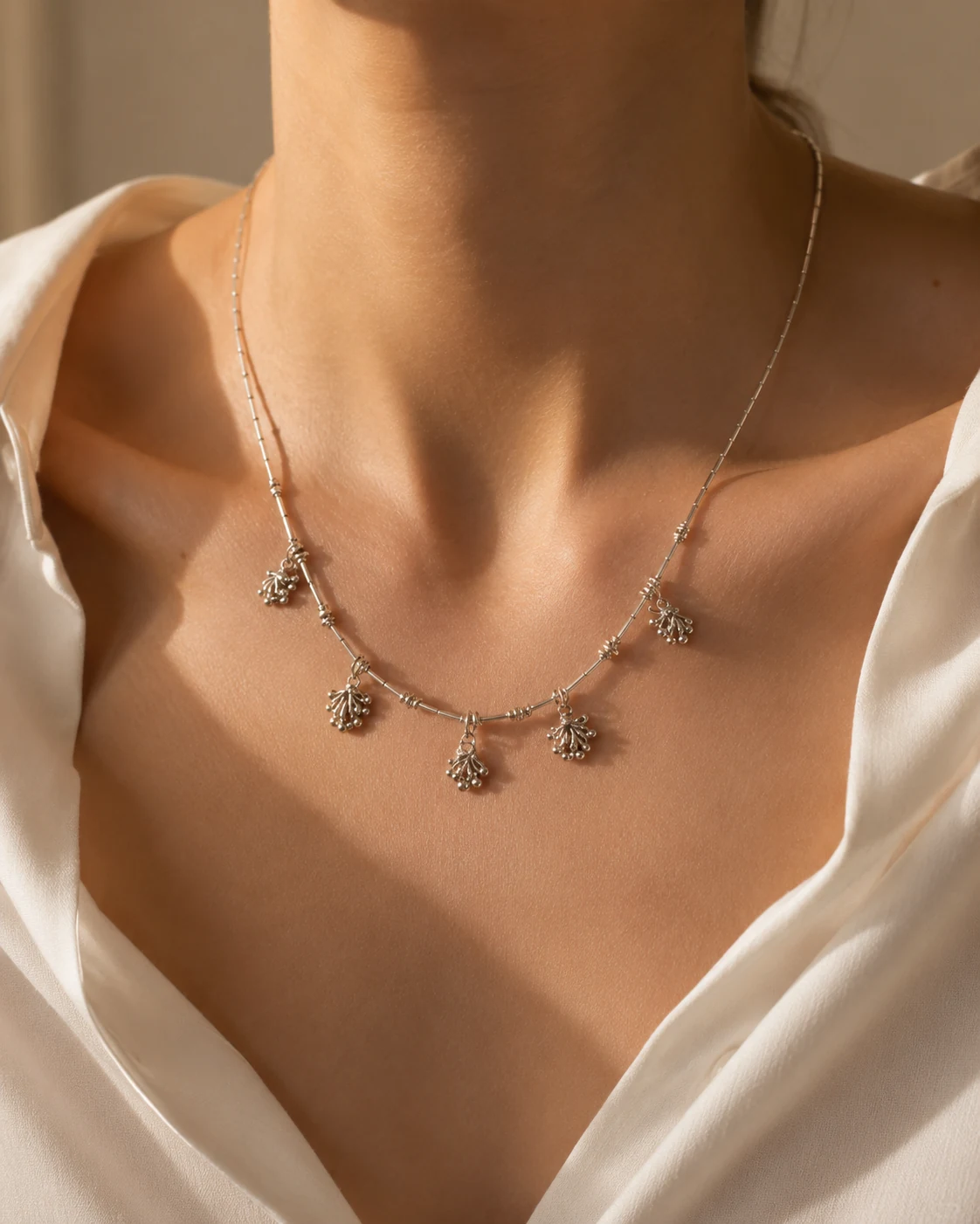 Silver necklace worn at the collarbone